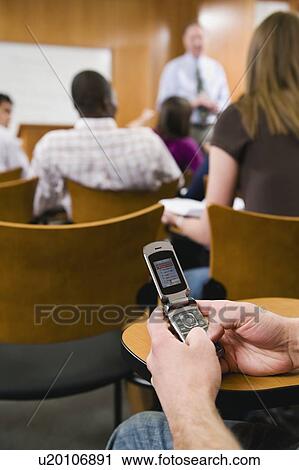 Stock Image - College student texting in lecture hall. Fotosearch