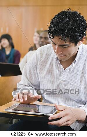 Picture - College students taking notes in lecture hall. Fotosearch