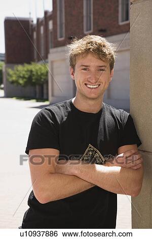 Confident teenage boy leaning against wall View Large Photo Image Stock Photograph - Confident teenage boy leaning against wall. Fotosearch