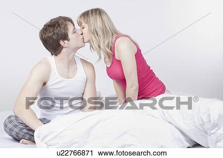 Stock Image - Couple kissing on bed. Fotosearch