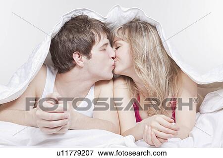 Couple kissing under the covers View Large Photo Image Stock Photo - Couple kissing under the covers. Fotosearch