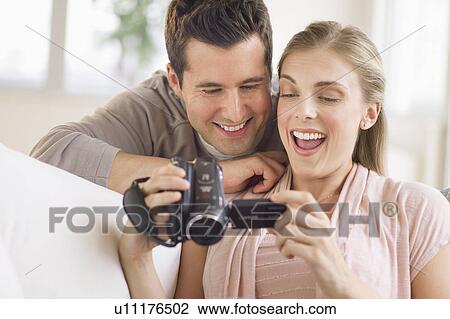 Stock Image - Couple looking at picture on video camera. Fotosearch