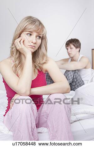 Stock Photo - Couple sitting on bed after arguing. Fotosearch