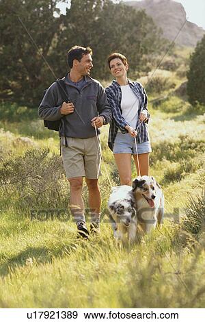 Couple walking their dogs in the countryside View Large Photo Image Stock Photo - Couple walking their dogs in the countryside. Fotosearch