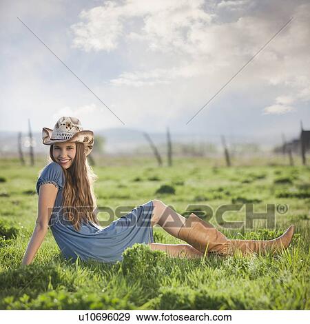 Stock Photo - Cowgirl relaxing in field. Fotosearch