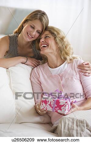 Daughter giving mother's day present to her mother View Large Photo Image Stock Photo - Daughter giving mother's day present to her mother. Fotosearch