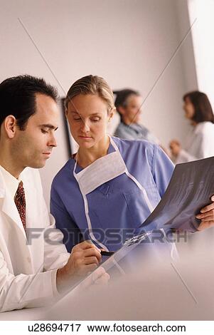 Stock Photo - Doctor and nurse looking at chart. Fotosearch