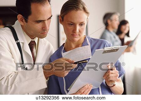 Stock Photograph - Doctor and nurse looking at chart. Fotosearch