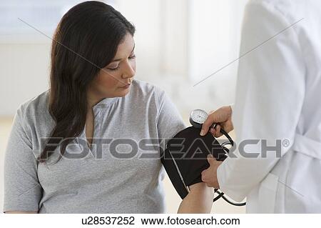Doctor checking woman's blood pressure View Large Photo Image Stock Image - Doctor checking woman's blood pressure. Fotosearch
