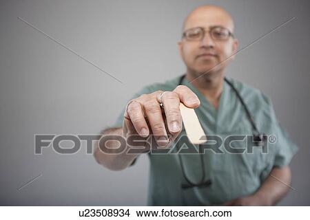 Picture - Doctor holding a tongue depressor. Fotosearch