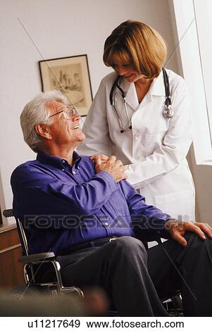 Stock Photo - Doctor talking to senior man in wheelchair. Fotosearch