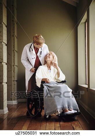 Stock Image - Doctor talking to woman in wheelchair. Fotosearch