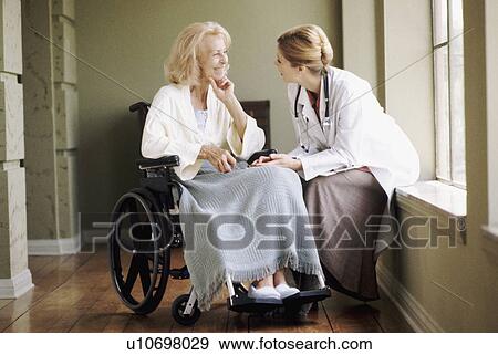 Stock Photo - Doctor talking to woman in wheelchair. Fotosearch
