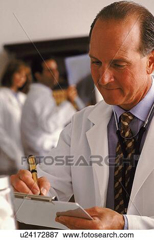 Doctor writing on his clipboard View Large Photo Image Stock Photo - Doctor writing on his clipboard. Fotosearch