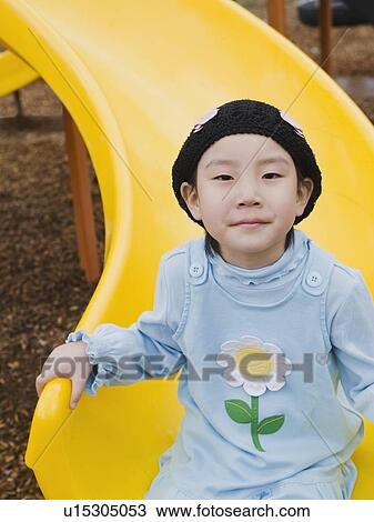 Stock Image - Elementary school student playing on slide at recess. Fotosearch