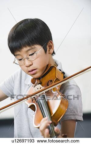 Stock Image - Elementary school student playing violin in music class. Fotosearch
