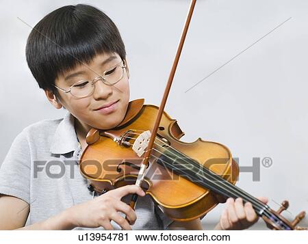 Stock Image - Elementary school student playing violin in music class. Fotosearch