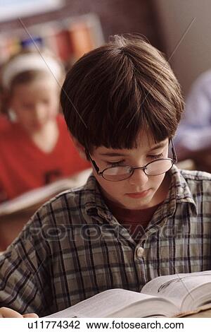 Stock Image - Elementary school student reading at his desk. Fotosearch