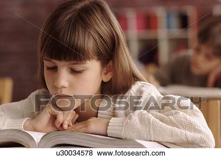 Elementary school student reading book at her desk View Large Photo Image Stock Photo - Elementary school student reading book at her desk. Fotosearch