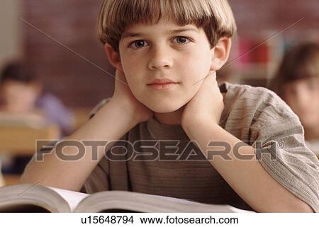 Picture - Elementary school student sitting at his desk. Fotosearch