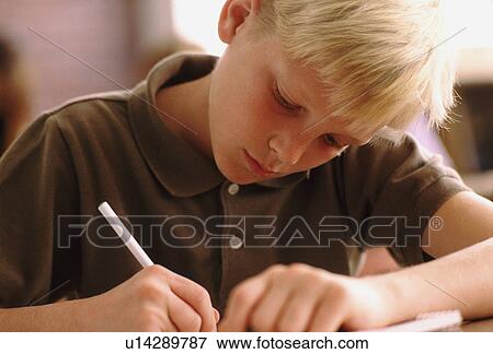 Stock Photo - Elementary school student writing at his desk. Fotosearch