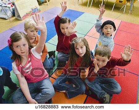 Stock Image - Elementary school students raising their hands. Fotosearch