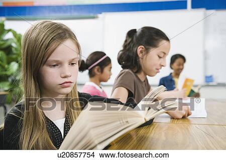Picture - Elementary school students reading books at desk. Fotosearch