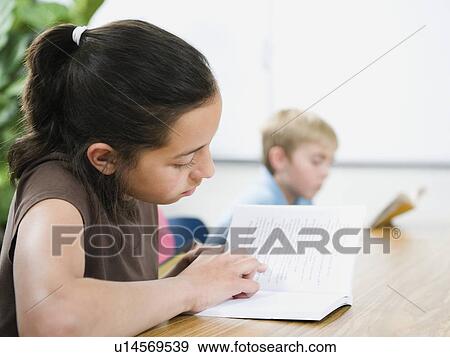 Elementary school students reading books at desk View Large Photo Image Stock Photo - Elementary school students reading books at desk. Fotosearch