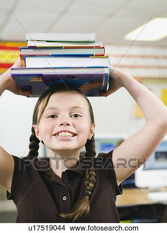 Elementary student holding a stack of books on her head View Large Photo Image Picture - Elementary student holding a stack of books on her head. Fotosearch