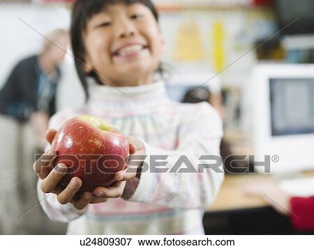 Stock Photo - Elementary student holding an apple in her hand. Fotosearch