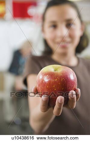 Elementary student holding an apple in her hand View Large Photo Image Stock Photograph - Elementary student holding an apple in her hand. Fotosearch