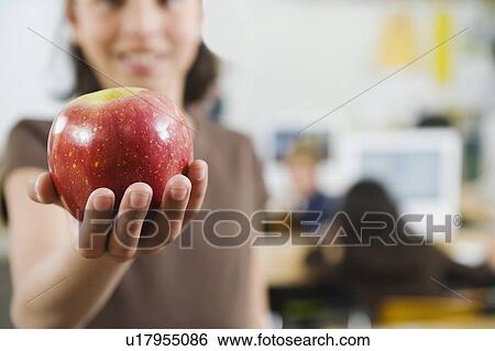 Stock Photograph - Elementary student holding an apple in her hand. Fotosearch