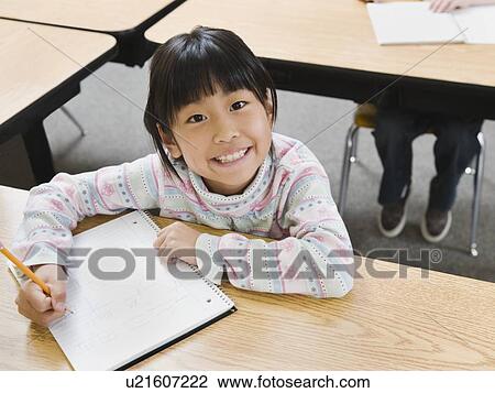 Stock Image - Elementary student writing in her notebook. Fotosearch