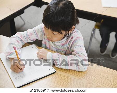 Stock Photo - Elementary student writing in her notebook. Fotosearch