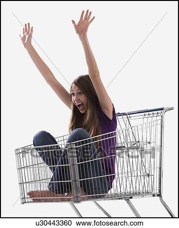Stock Image - Excited woman sitting in a shopping cart. Fotosearch