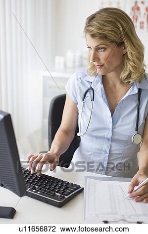 Stock Image - Female doctor working at her desk. Fotosearch