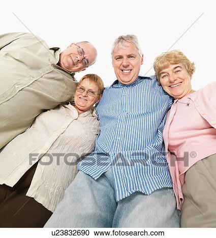 Stock Image - Four friends standing with their arms around each other. Fotosearch