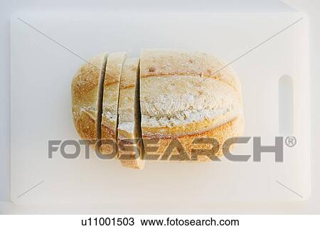 Stock Image - Freshly sliced bread on cutting board. Fotosearch