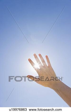 Stock Image - Hand held up in front of sunshine. Fotosearch