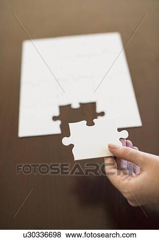 Stock Photo - Hand putting last puzzle piece in puzzle. Fotosearch