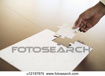 Stock Photography - Hand putting last puzzle piece in puzzle. Fotosearch
