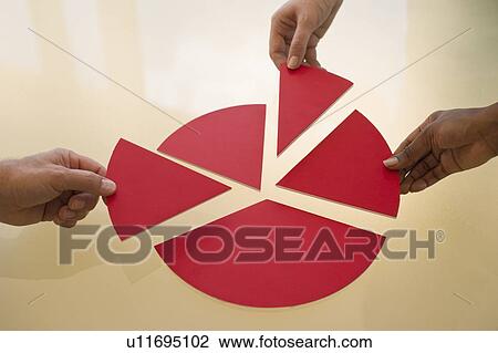 Stock Image - Hands dividing pieces of pie chart. Fotosearch