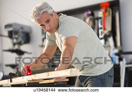 Handyman measuring a piece of wood in workshop View Large Photo Image Picture - Handyman measuring a piece of wood in workshop. Fotosearch