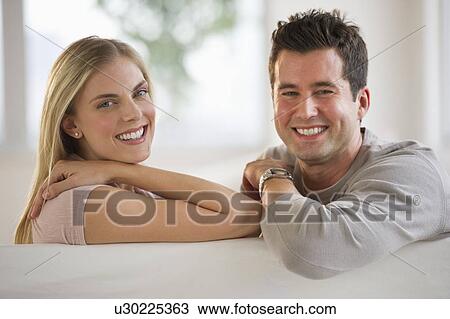 Stock Image - Happy couple relaxing on couch. Fotosearch