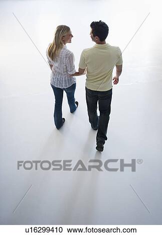 Stock Image - Happy couple walking hand in hand. Fotosearch
