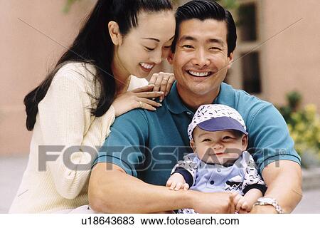 Happy parents sitting with their infant son View Large Photo Image Stock Image - Happy parents sitting with their infant son. Fotosearch