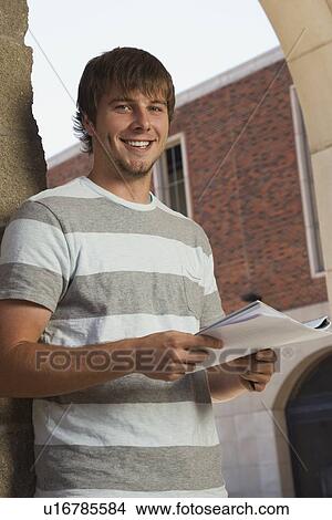 Happy teenage boy holding schoolwork View Large Photo Image Picture - Happy teenage boy holding schoolwork. Fotosearch
