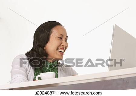 Stock Image - Happy woman looking at laptop. Fotosearch