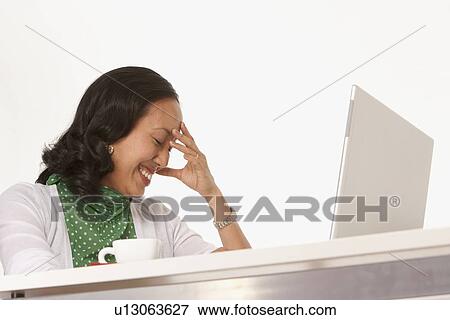 Stock Photo - Happy woman looking at laptop. Fotosearch