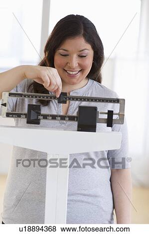 Happy woman standing on scale View Large Photo Image Stock Photo - Happy woman standing on scale. Fotosearch